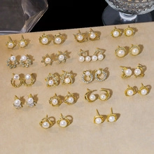 Detail of assorted gold pearl earrings with rhinestone accents on a beige display