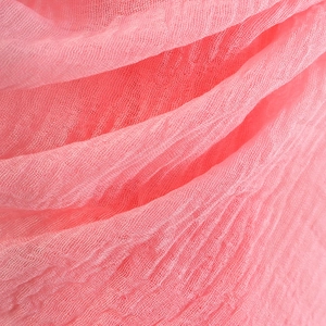 Close-up of pink crinkled cotton linen scarf showing detailed textile texture and fringe