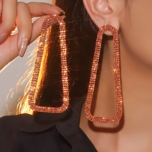 Close-up of oversized rose gold rectangular earrings with sparkling black rhinestones