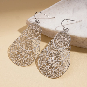 Détail de boucles d'oreilles en métal en forme de goutte avec motifs floraux ajourés