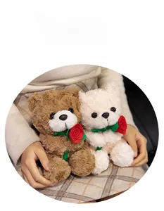 Close-up of soft plush teddy bears in brown and cream holding red textile roses