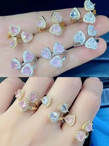 Primo piano di anelli con gemme a cuore rosa e diamanti micro-pavé sulle dita