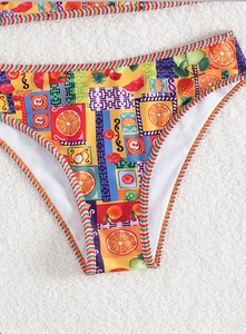 Detail einer Bikini-Hose mit tropischem Fruchtdruck und buntem gestreiftem Rand