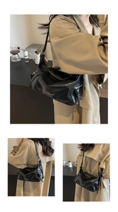 Detailed close-up of black pebbled leather texture and silver zipper on the shoulder bag