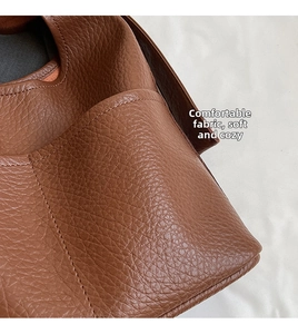 Gros plan du cuir grainé marron caramel avec surpiqûres détaillées sur le grand sac