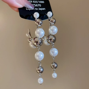 Macro shot of silver C-shape earrings with white pearls and 925 silver needles detail