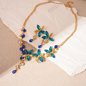 Vintage gold jewelry set with blue floral rhinestones and teardrop tassels on white stone