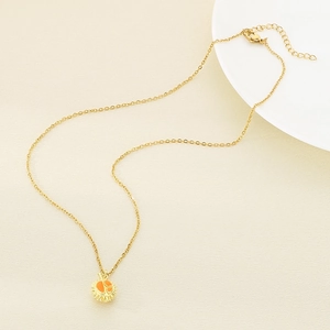 Golden titanium steel necklace with a vibrant orange enamel sunburst pendant on beige surface