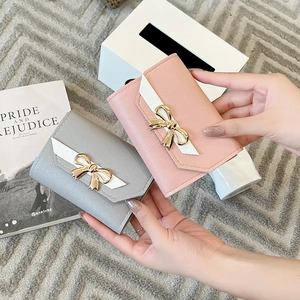 Detail of pink and gray PU leather wallets with gold bow buckles and woven straps