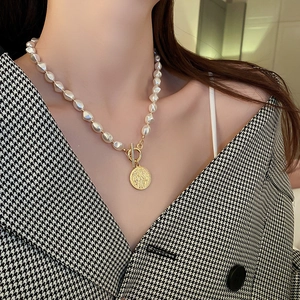Detail view of the elegant Baroque pearl necklace with a vintage golden coin pendant and OT toggle