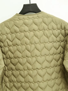 Close-up of olive green quilted jacket featuring unique heart-shaped stitching patterns