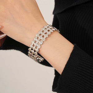 Detailed view of a silver wide hollow woven mesh bracelet worn on a woman wrist