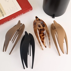 Top view of four large matte and tortoiseshell hair claws on a clean white background