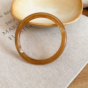 Détail macro d'une bague en résine ambrée texturée posée sur un plateau en céramique