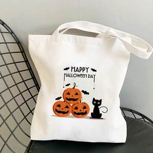 Détail d'un sac cabas en toile blanche avec motif citrouille d'Halloween et chat sur une chaise