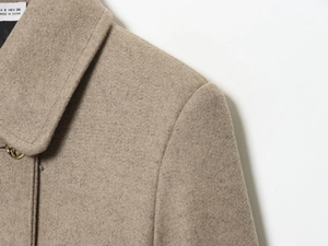 Detailed close-up of wool blend coat collar with a textured golden embossed button