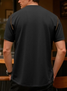 Detail of breathable honeycomb fabric and orange contrast stitching on black polo shirt