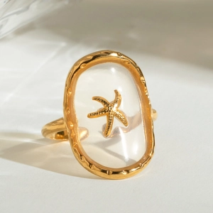 Macro shot of gold starfish encased in clear oval resin on a stainless steel ring