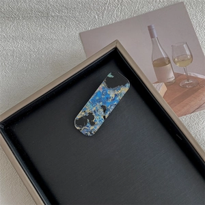 Detailed macro view of acetate hair clip with vintage marble texture on a black tray
