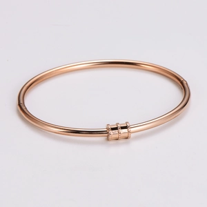 Close-up of rose gold minimalist bangle with three textured cylindrical sliders and clasp