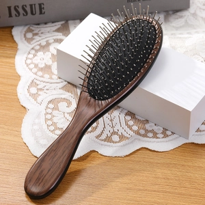 Λεπτομέρεια ξύλινης βούρτσας μαλλιών με μεταλλικά δόντια και μαύρο μαξιλαράκι