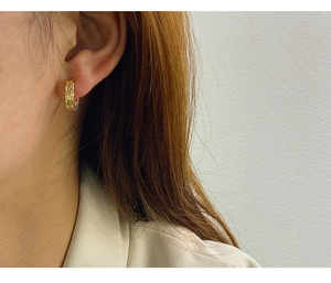 Close-up of golden lava texture square earrings worn by a model to show size and fit