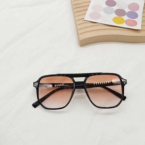 Detail of square vintage sunglasses with double-bridge black frame and orange gradient lenses