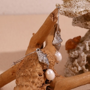 Detailed shot of silver conch shell earrings with freshwater pearls on coral and wood