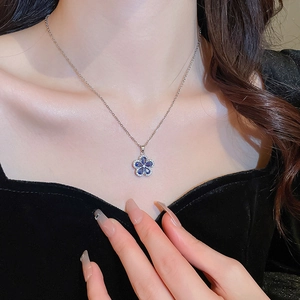 Close-up of blue five-petal flower pendant necklace with diamonds on woman's neck