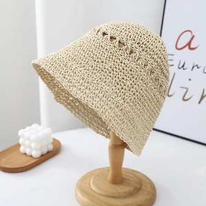 Detail of oat beige straw bucket hat featuring intricate woven patterns and wavy hollow top