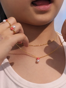 Primer plano de niña con collar de estrella de mar dorada y set de anillos de perlas