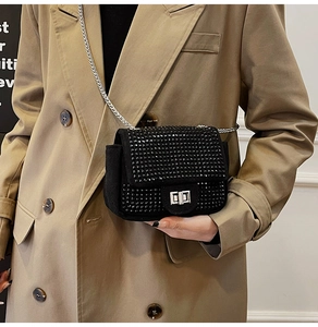 Detail of a black rhinestone mini chain bag with a silver metal twist lock closure