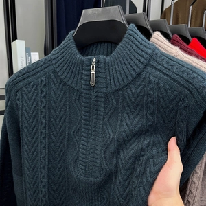 Detail of dark green cable knit sweater featuring a metal half-zip neckline and texture