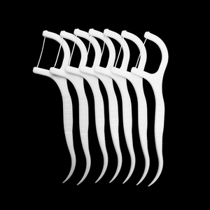 Macro shot of seven white plastic dental floss picks with sharp toothpick ends on black background