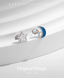 Macro view of S925 silver asymmetric star and moon earrings with blue enamel detail