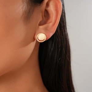 Gros plan d'une boucle d'oreille ronde dorée avec incrustation de nacre sur un modèle