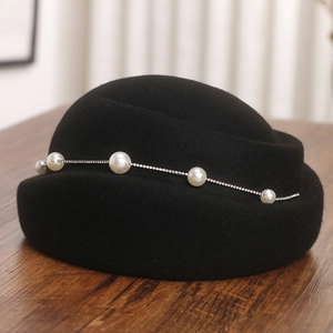 Détail du béret élégant en laine noire avec une chaîne délicate de perles et de strass