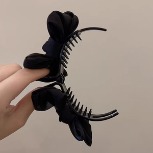 Elegant black bow hair claw clip for bun hairstyles, side view showing claw teeth detail