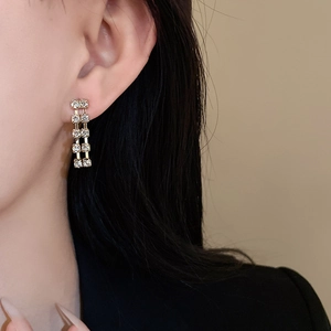 Close-up of gold drop earrings with double row of square cubic zirconia stones