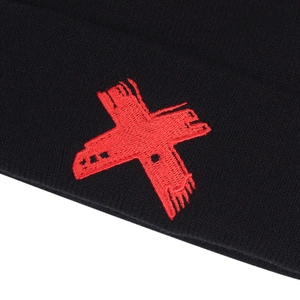 Gros plan d'un bonnet en tricot noir avec un logo X brodé rouge aux détails texturés