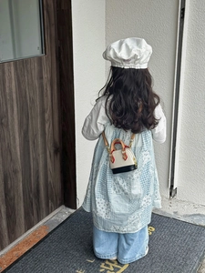 Kleinkind Mädchen mit einer beige-schwarzen Muschel-Umhängetasche mit braunem Griff