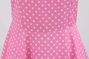 Close-up detail of pink polka dot dress showing high-waisted seam and woven fabric texture