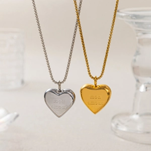 Macro shot of gold and silver heart pendants engraved with mon amour in 18k gold plating