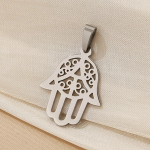Macro shot of silver Hamsa Hand pendant with intricate hollow design on silk fabric