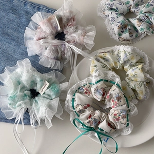 Detail of four floral lace scrunchies with ribbons on white background and denim fabric