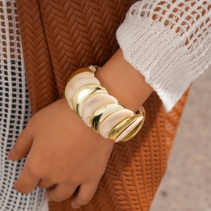 Dettaglio di un largo bracciale boho con dischi in metallo dorato e resina marmorizzata