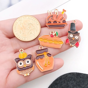 Thanksgiving enamel pendants including turkey and pumpkin next to a dollar coin