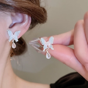Détail de boucles d'oreilles nœud floral bleu avec breloques gouttes sur un modèle