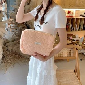 Close-up of pink heart quilted cosmetic bag with woven label in a cozy cafe setting