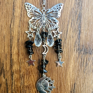 Detail of silver butterfly suncatcher with crystal pendants and moon motifs on wood